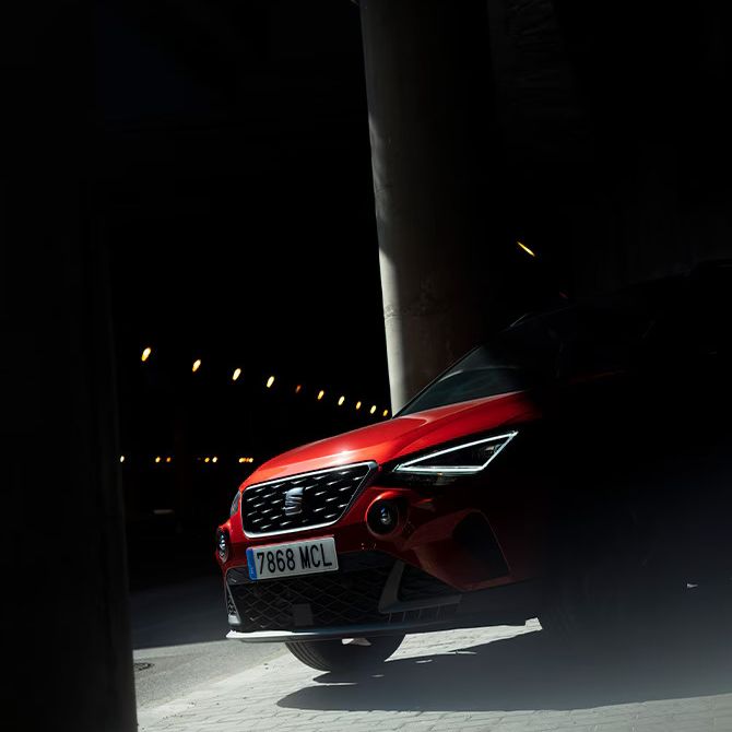 Vista frontal do SEAT Arona na cor vermelho Desire, estacionado.