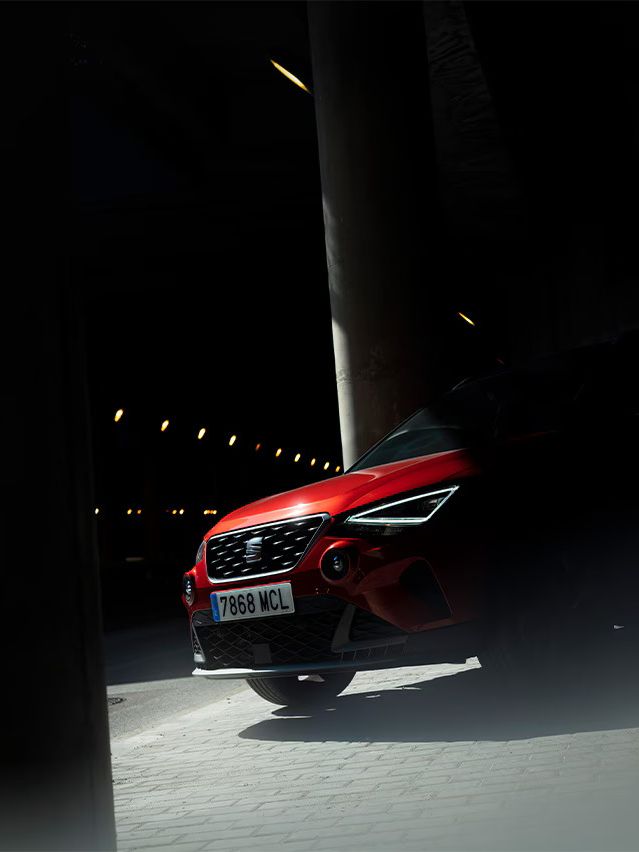 Vista frontal do SEAT Arona na cor vermelho Desire, estacionado.