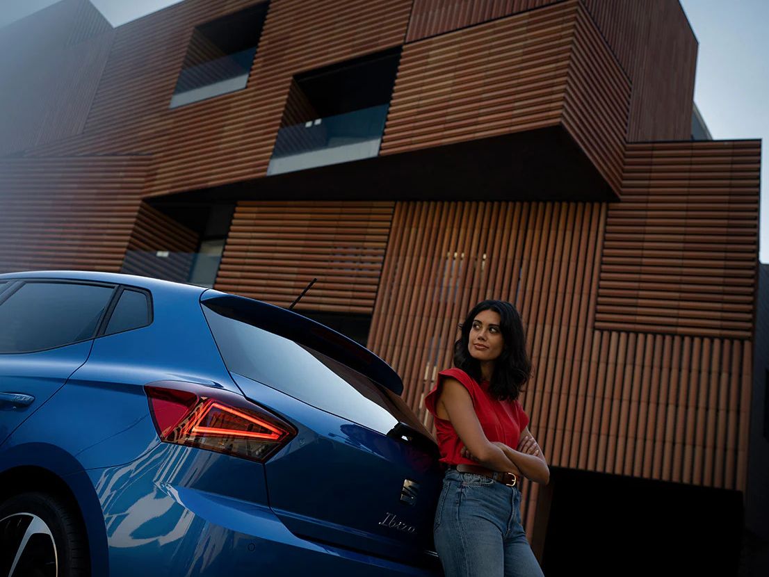 > Mulher apoiada no SEAT Ibiza em Azul Safira