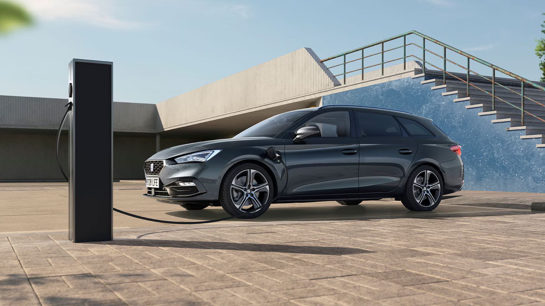 Vista lateral de um carro híbrido plug-in da SEAT, estacionado e a carregar numa zona semiaberta com sol parcial, destacando a condução eficiente e o respeito pelo ambiente, com redução de emissões. 