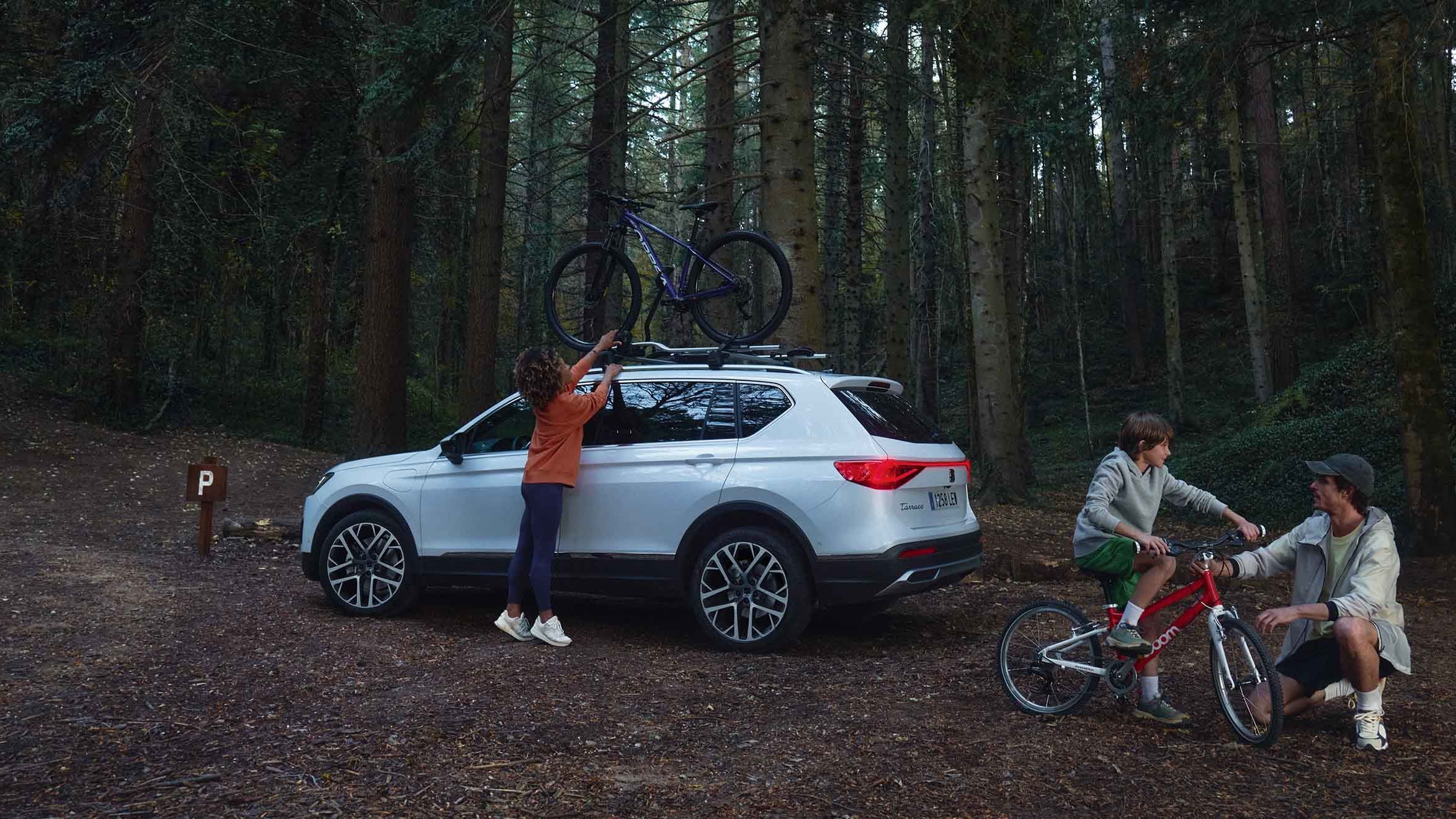 Família na floresta com o seu SEAT Ateca, equipado com suporte de bicicletas, ideal para aventuras ao ar livre.