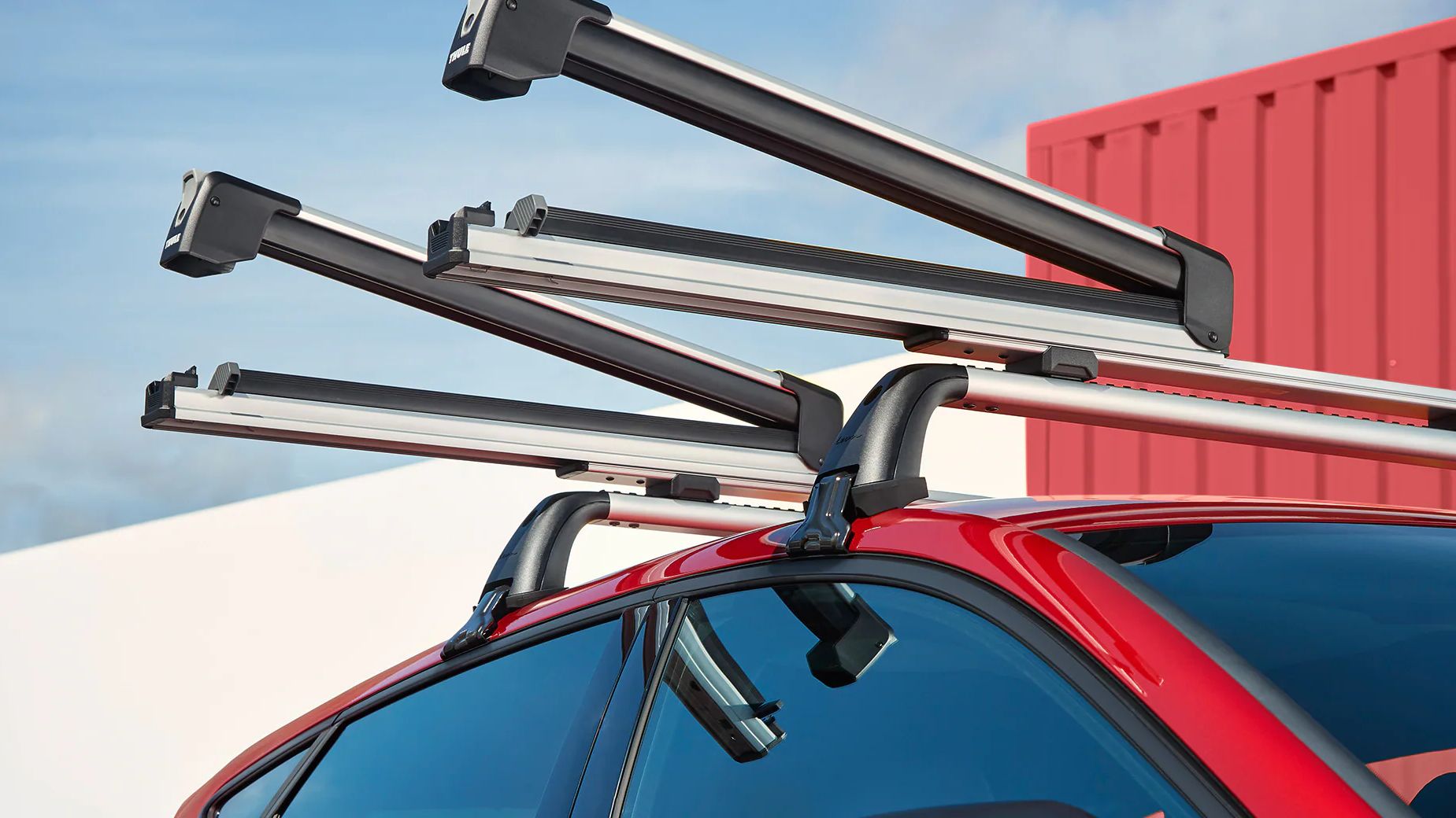 Amigos a colocarem os skis nas barras de tejadilho no SEAT Leon vermelho desire 