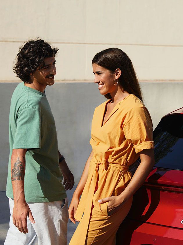 Casal a conversar junto SEAT Leon na cor Vermelho Desire no inverno