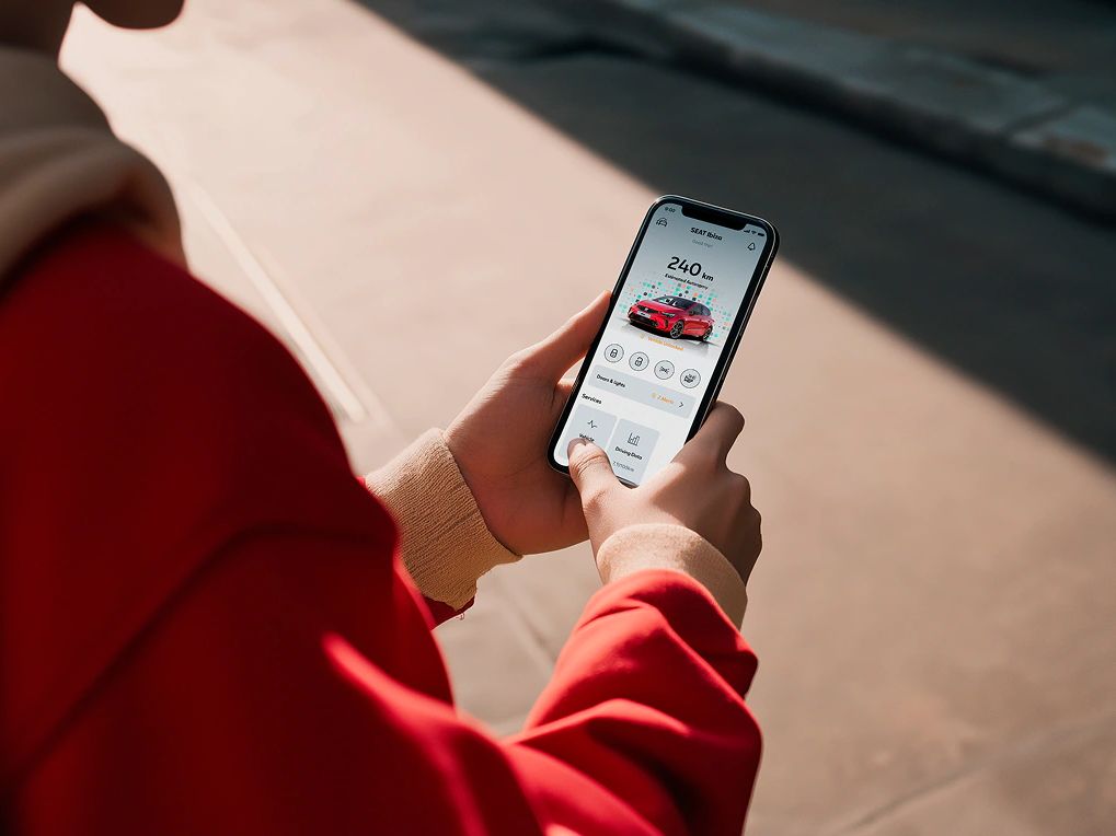 Pessoa a segurar o smartphone a utilizar as funções remotas da SEAT. 