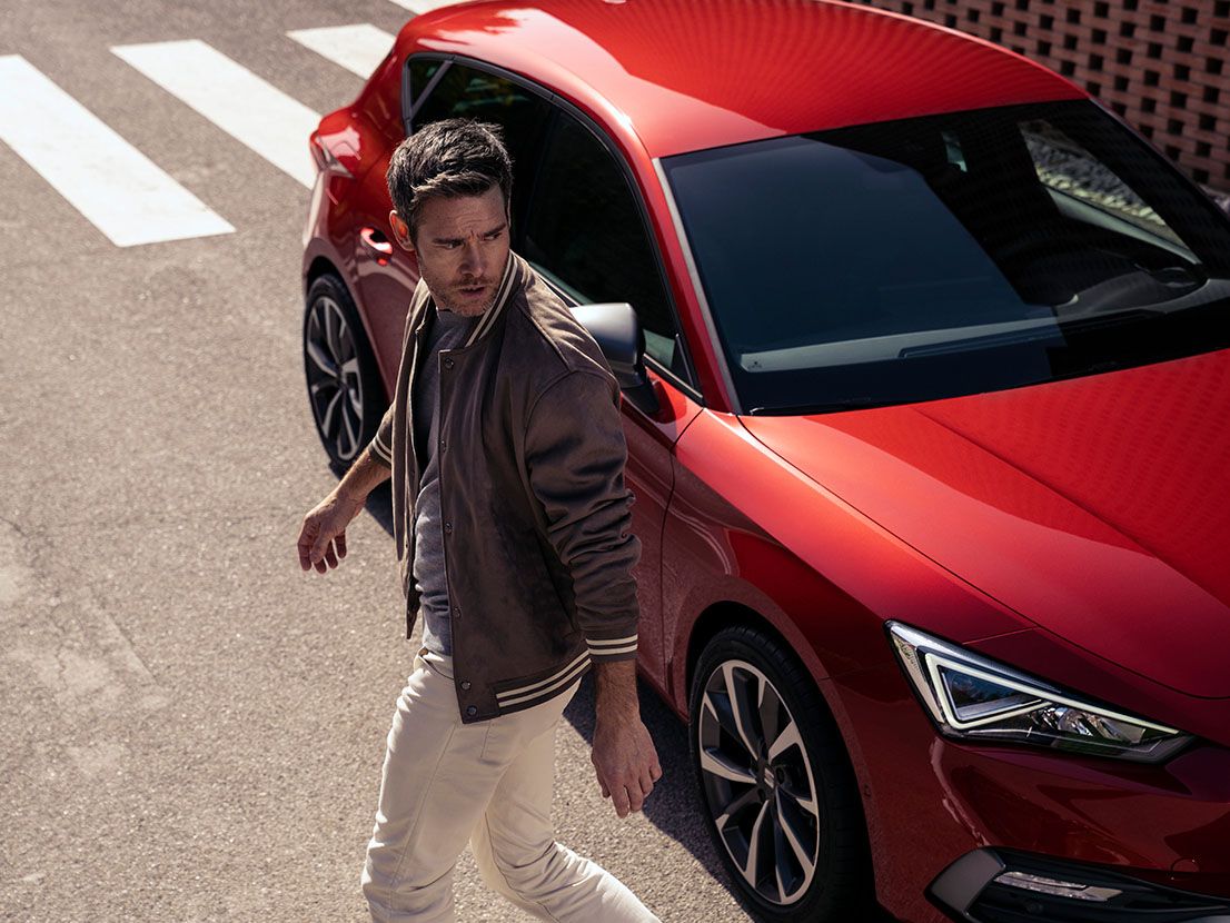 SEAT Leon vermelho em movimento junto a edifícios modernos