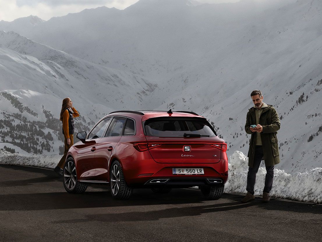 SEAT Leon vermelho estacionado numa estrada de montanha, com duas pessoas perto à espera do  SEAT Service Mobilidade