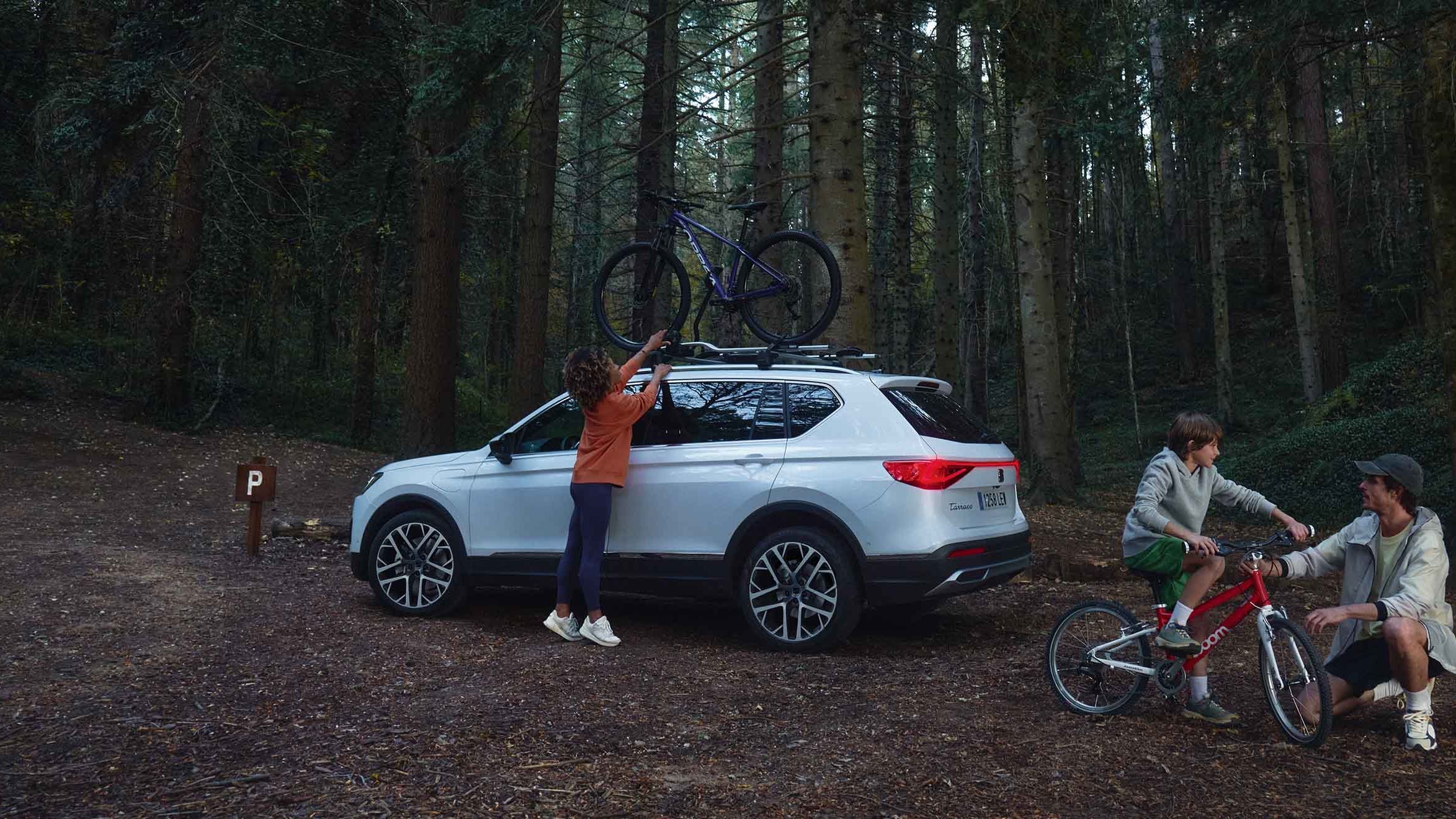 Família na floresta com o seu SEAT Ateca, equipado com suporte de bicicletas, ideal para aventuras ao ar livre.