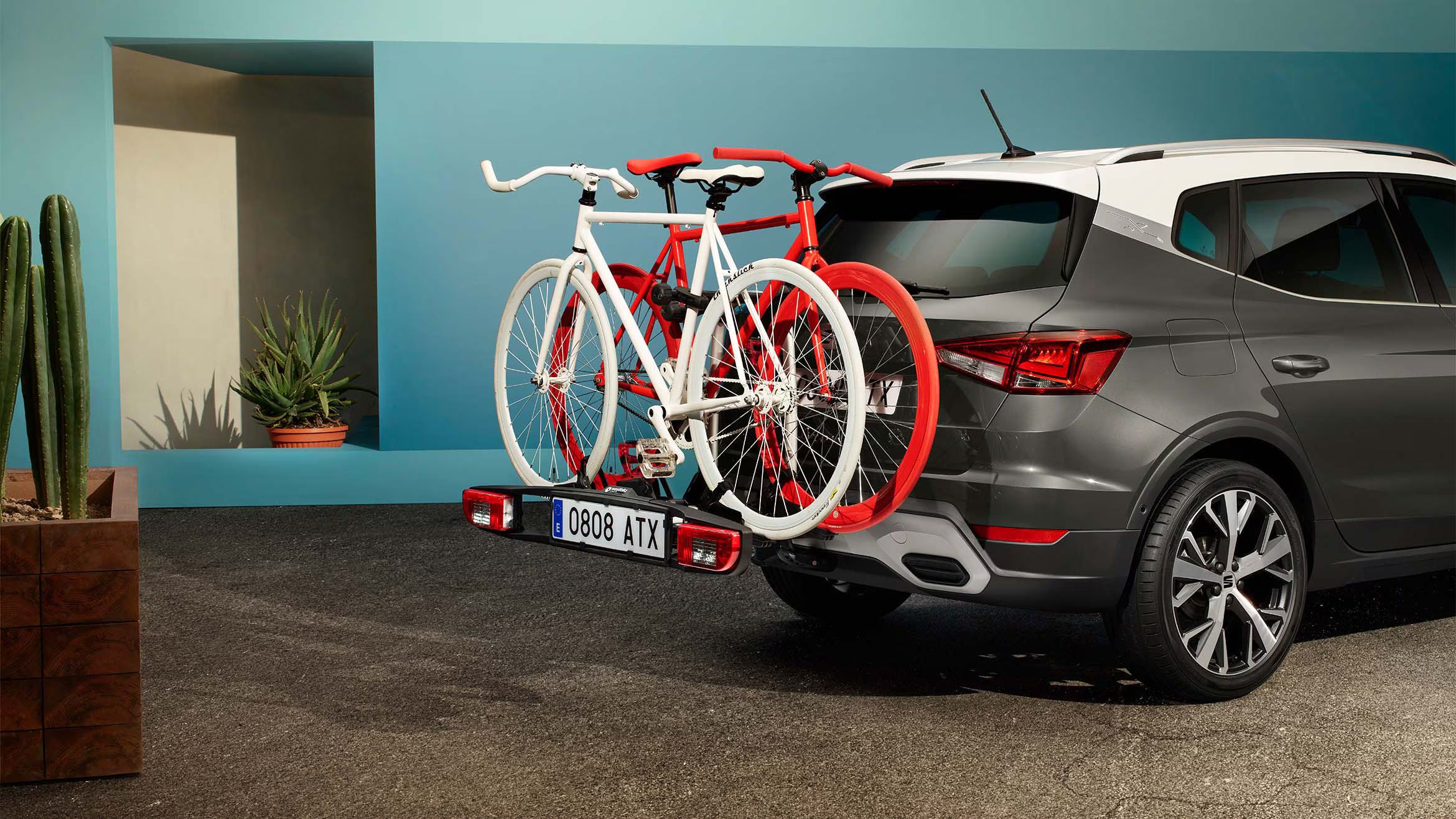 SEAT Arona preto com tejadilho branco e bicicletas no suporte traseiro, estacionado ao ar livre.